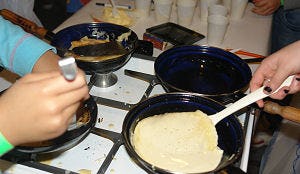 Basisschoolleerlingen bakken pannenkoeken voor zorgbewoners
