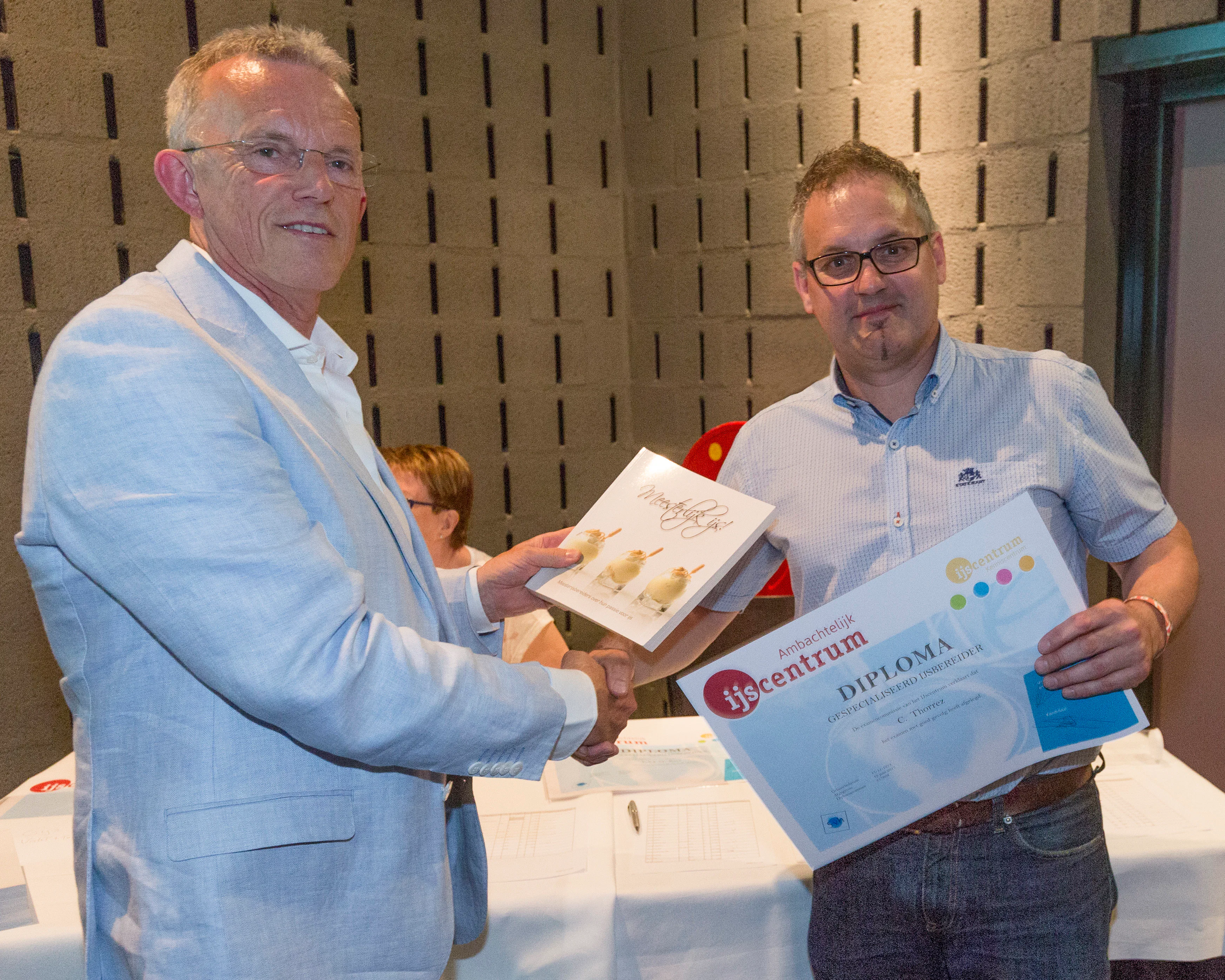 Christof Thorrez (rechts) is de eerste Belg die een Nederlands ijsdiploma behaalde, hier overhandigd door voorzitter Jacques Vos. Hij slaagde voor de cursus Gespecialiseerd IJsbereider. Foto: Studio38C