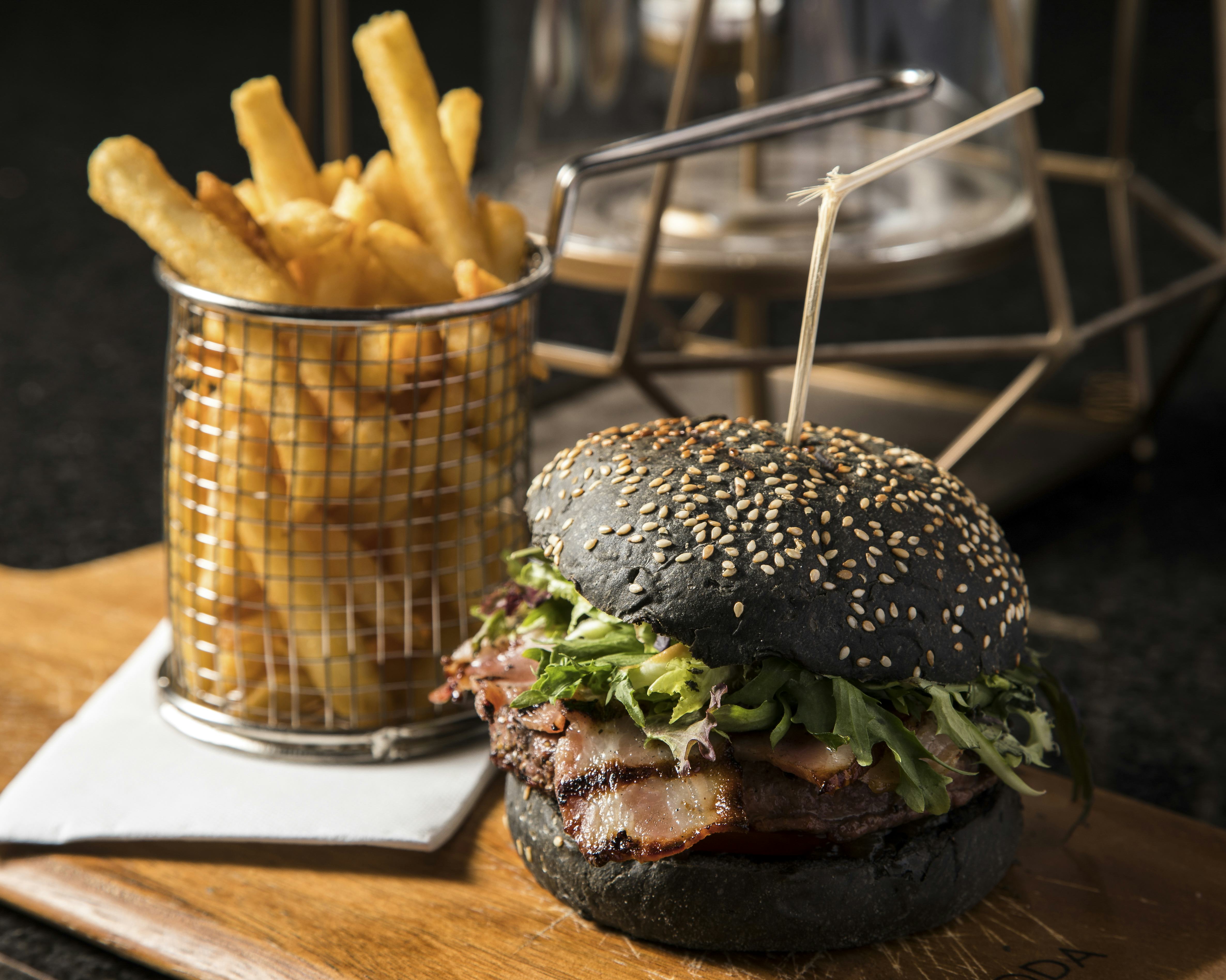 Full shot of a black hamburger and fries on a table