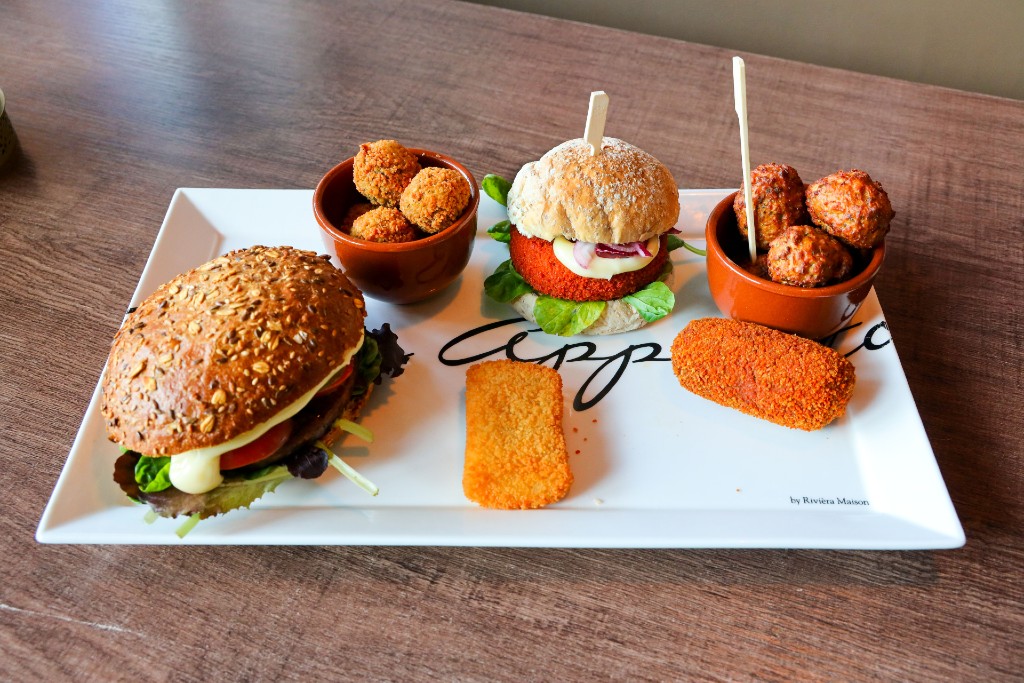 Vegetarisch snacken bij Chez Mariëlle in Eindhoven: een broodje vegetarische bamischijf, een broodje vegetarische kipcorn, vegetarische gehaktballetjes en de vegaburger op een bruine bol.