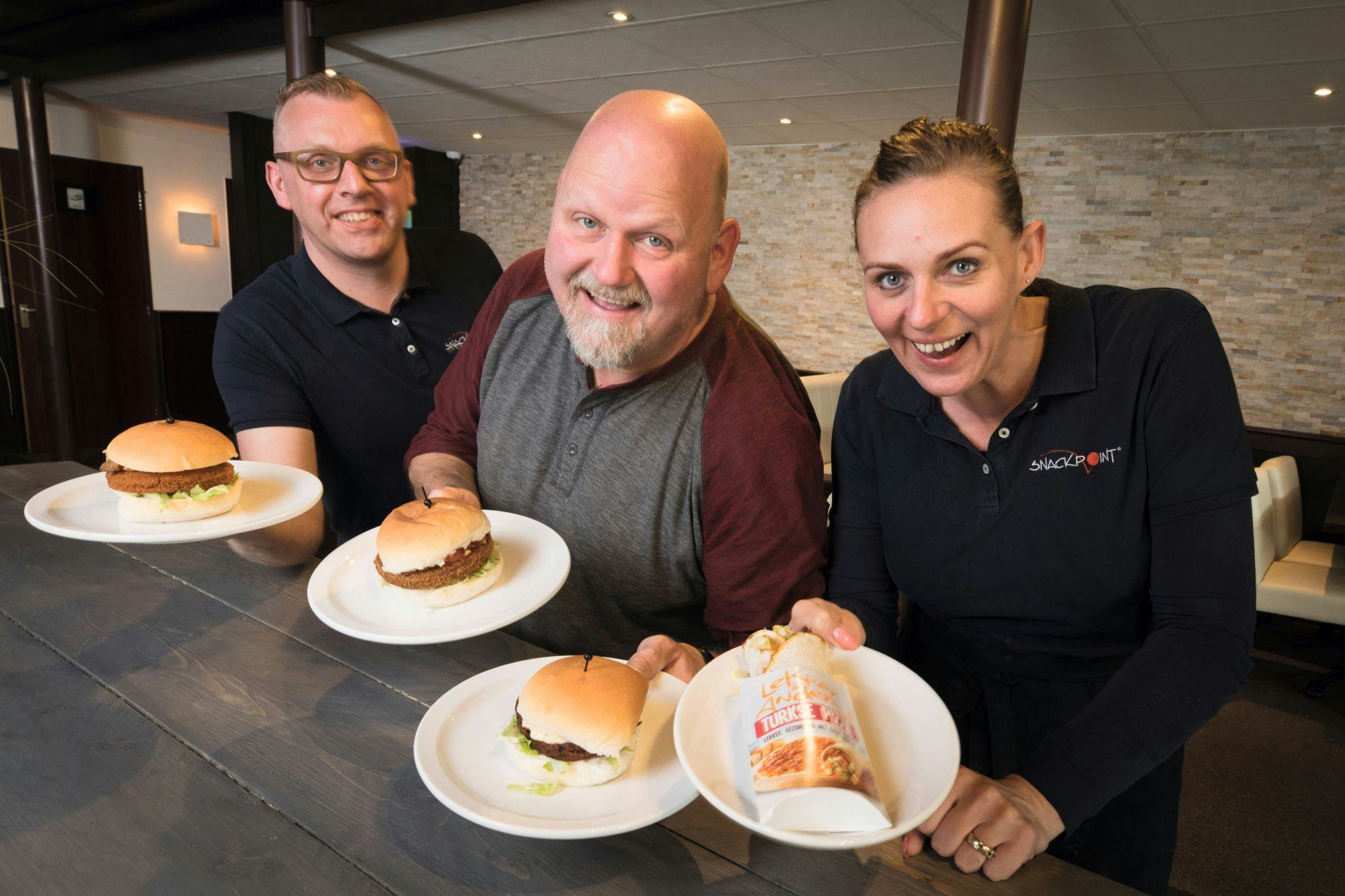 Jacques van Dijk en Corine Speijers van Snackpoint ‘t Smulhoekje in Herveld presenteren samen met Roger Gielen de vegetarische burgers en de pizzawrap.
