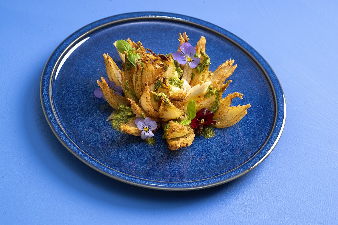 De vegan pesto kan gebruikt worden als pastasaus, op gegrilde groenten, met brood of zoals op de foto met een gefrituurde ui.